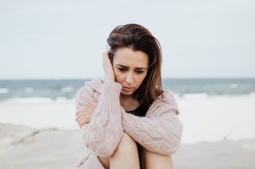 Free Woman in Pink Sweater Sitting on Beach Stock Photo