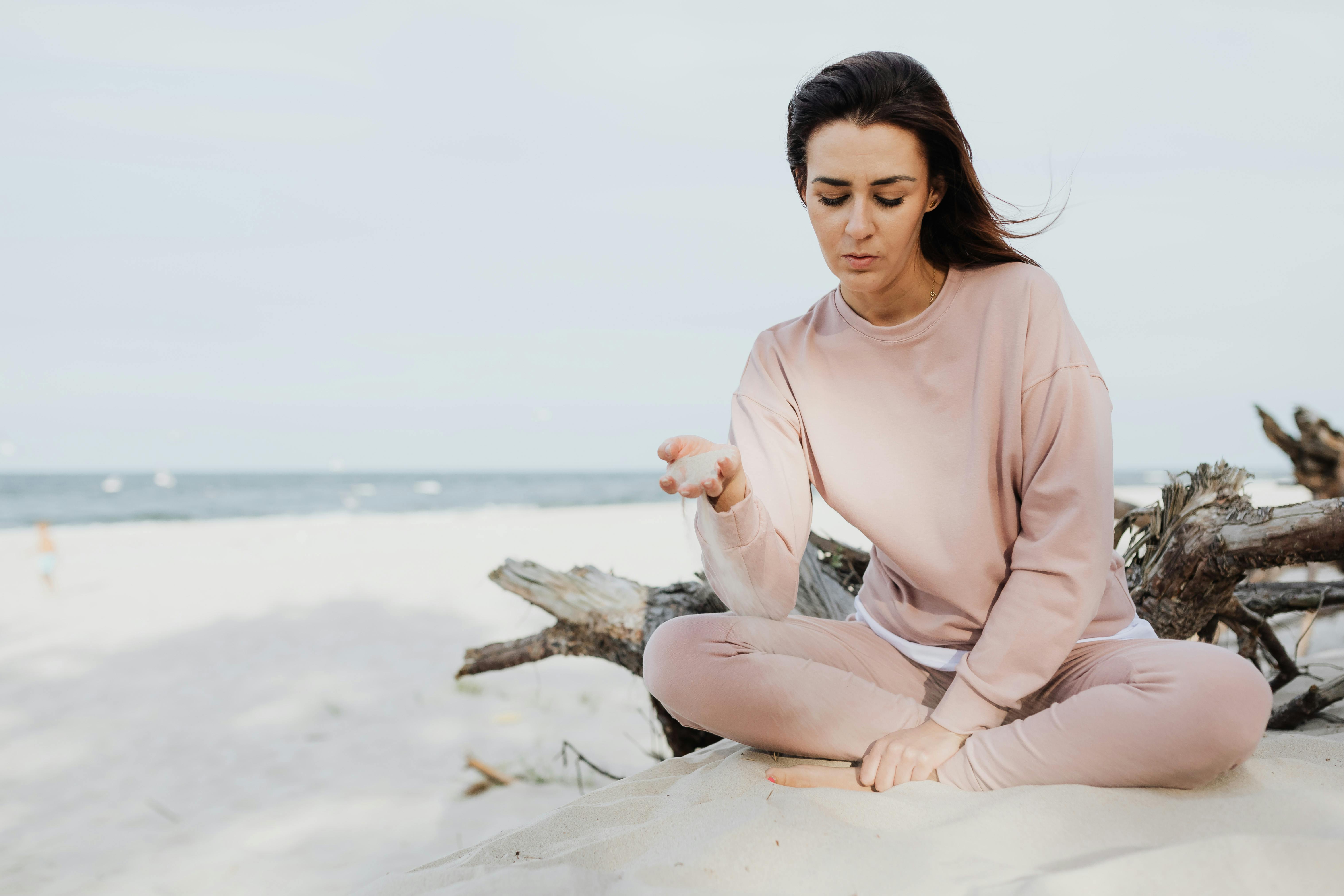 woman in long sleeve shirt sitting and playing with white sand