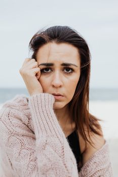 海滩边，穿着软毛衣的女人神情忧郁