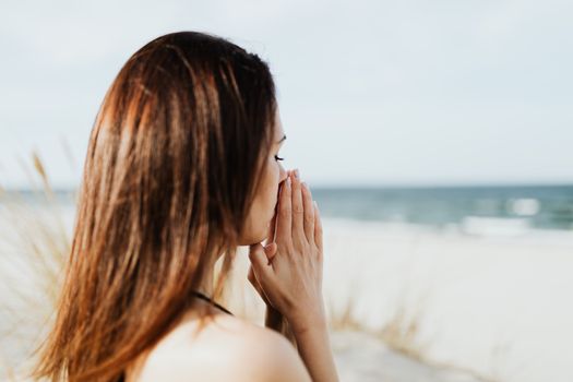 女人在海滩边双手合十，冥想中拥抱宁静与和平