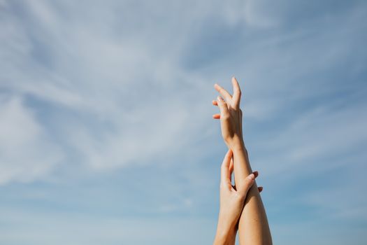 两只成年人的手伸向清澈的蓝天，象征着自由与渴望