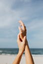 宁静的海滩场景，双手优雅地举起，映衬着晴朗的天空