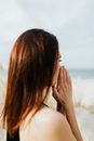 一名妇女在海滩上双手合十祈祷，这是她表达信仰的侧面图