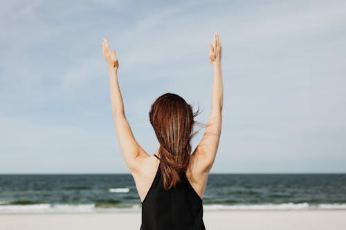 Woman Standing on the Beach Raising her Hands 