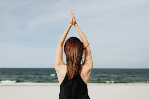 Woman at the Beach Raising her Pressed Hands over Her Head 