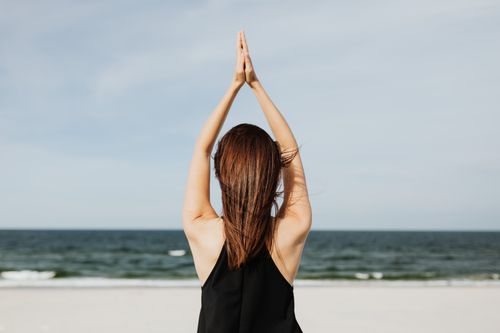 Free Back view of a woman practicing yoga by the sea, embracing peace and tranquility. Stock Photo