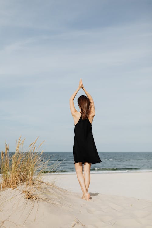 Woman Standing While Raising her Pressed Hands over Her Head 