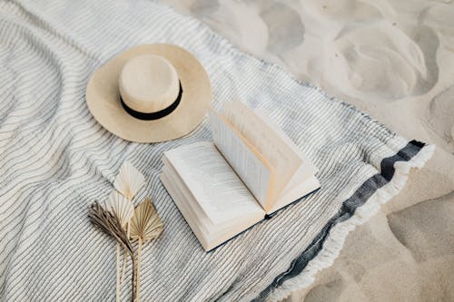 Free A Sun Hat and a Book On a Beach Towel Stock Photo