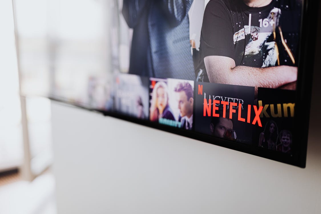 Free Black Flat Screen Tv Turned on Showing Man in Black Shirt Stock Photo