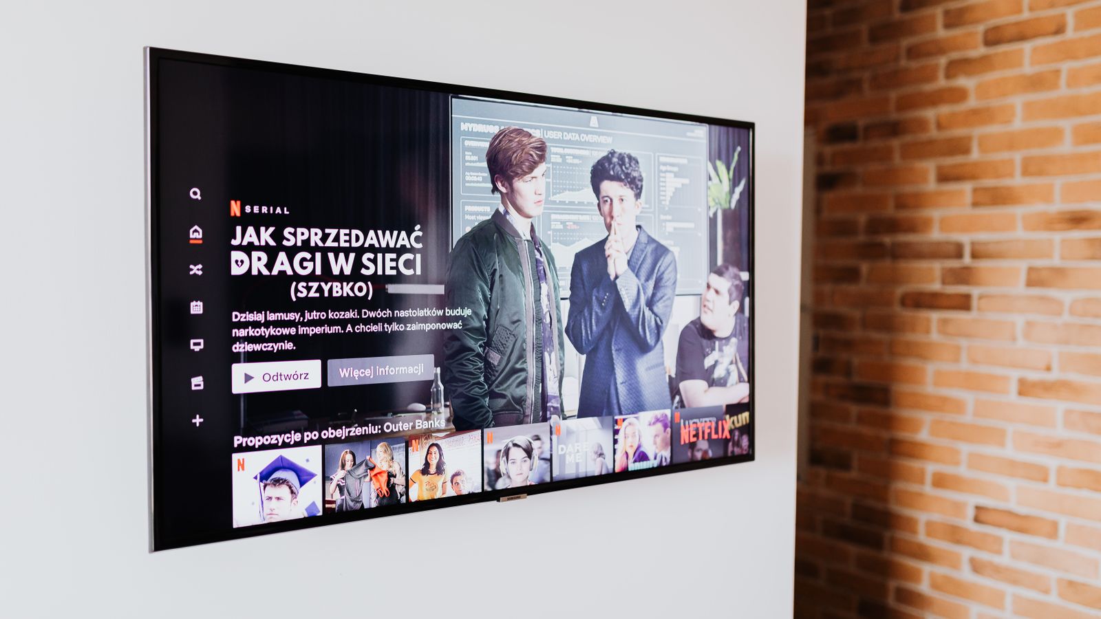 A smart television showing streaming content in a living room with a brick wall