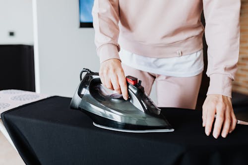 Person in Sweater Ironing a Dress
