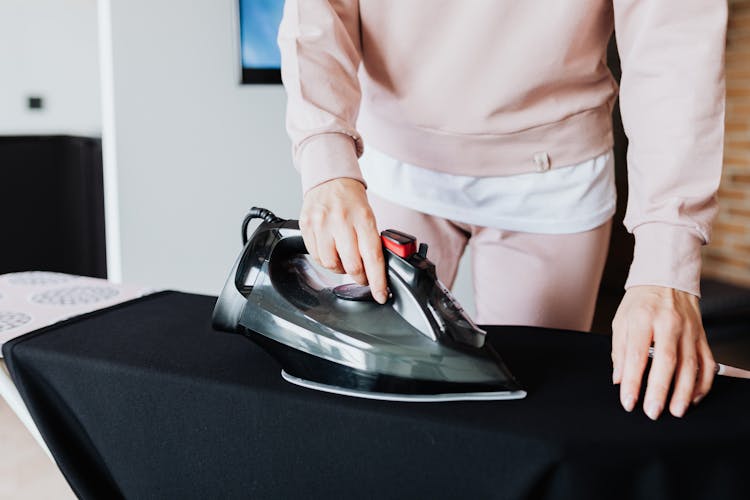 Person In Sweater Ironing A Dress