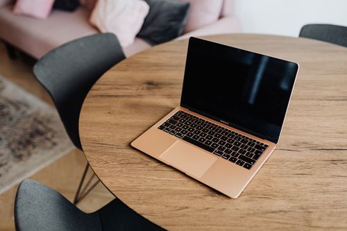 Free A modern laptop rests on a stylish round wooden table in a cozy room setting. Stock Photo