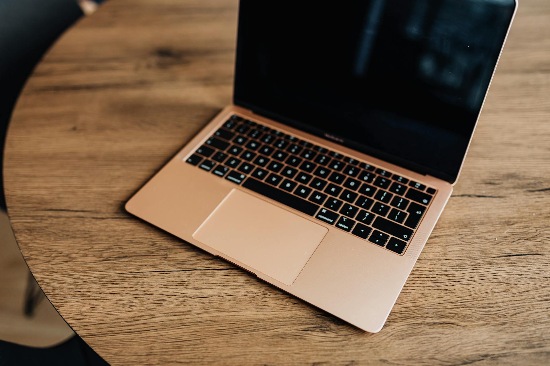 Golden laptop on a wooden table, viewed from above, showcasing modern design and sleek aesthetics.