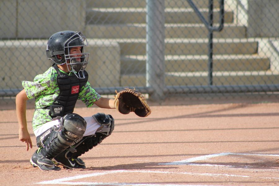 Baseball catcher crouched behind home plate giving hand signals