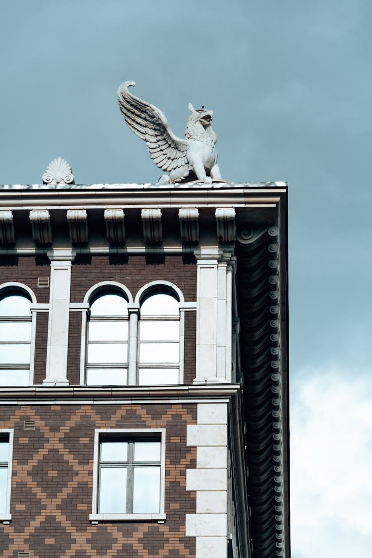 Old House Facade With Statue Of Griffon On Roof