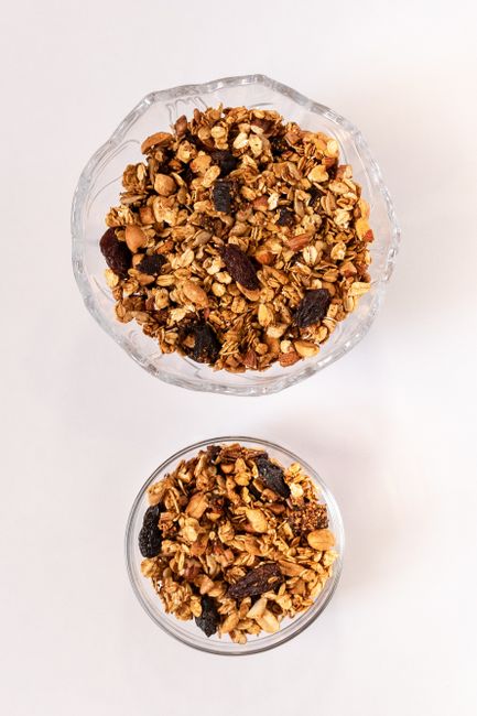 Top view of two bowls of nutritious granola with nuts and dried fruits on a white background. - best dry fruits for health goals