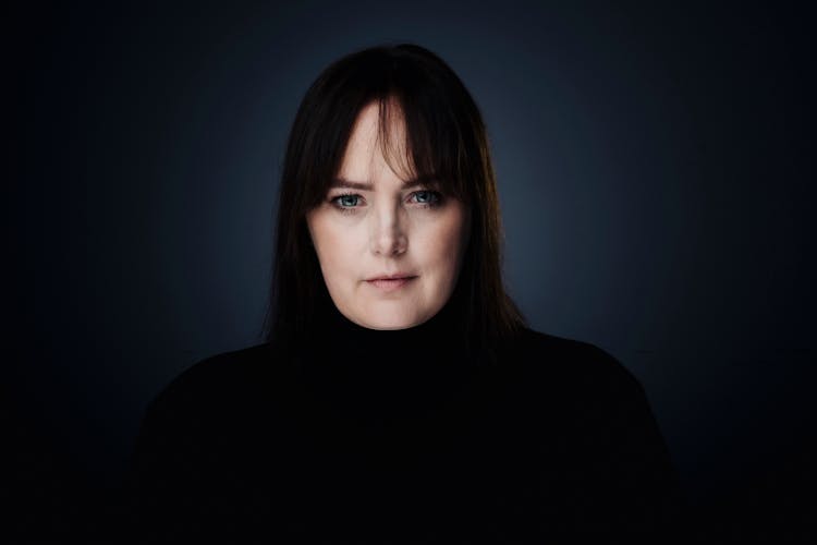 Portrait Of Brunette Woman In Black Clothes On Studio Background