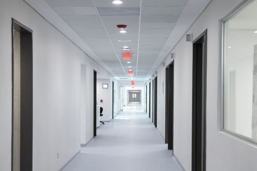White-walled hospital corridor with modern design and bright overhead lighting.