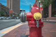 Empty paved sidewalk with red metal fire hydrant at roadside against blue sky in modern city