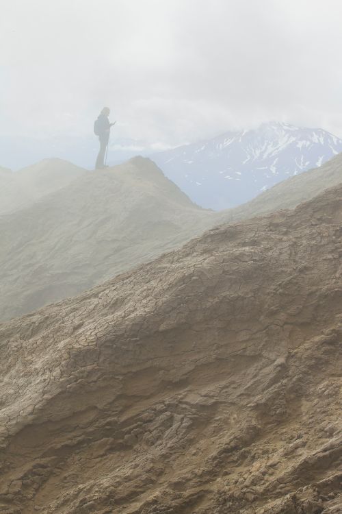 Free A lone hiker stands silhouetted against the foggy, rugged terrain of the Kamchatka mountains. Stock Photo