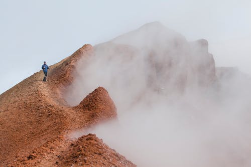 Free Man in Blue Jacket  Standing on Top of a Mountain Stock Photo