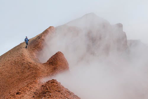 Man in Blue Jacket  Standing on Top of a Mountain