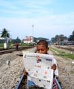 Boy in White Shirt Reading Newspaper