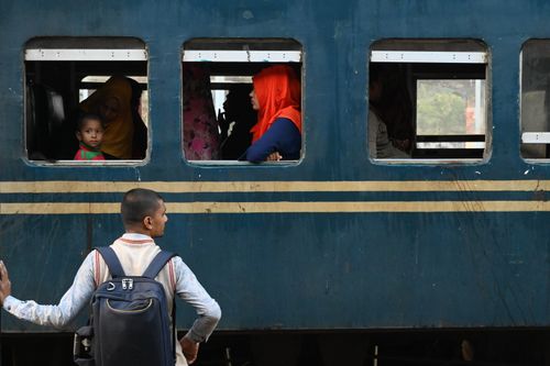 Free Passengers wait and observe the bustling train station in Chittagong, Bangladesh. Stock Photo