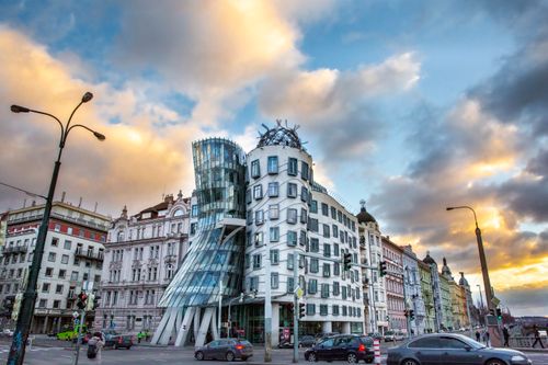 Free The Dancing House in Prague captured at sunset with a dramatic sky and street activity. Stock Photo