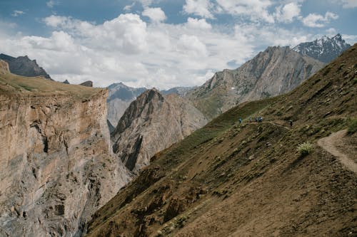 Breathtaking scenery of huge rocky mountain range with sharp peaks against cloudy blue sky