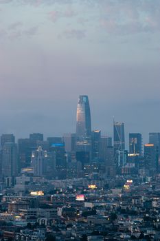 Aerial view of contemporary city with skyscrapers surrounded by residential buildings under colorful sky