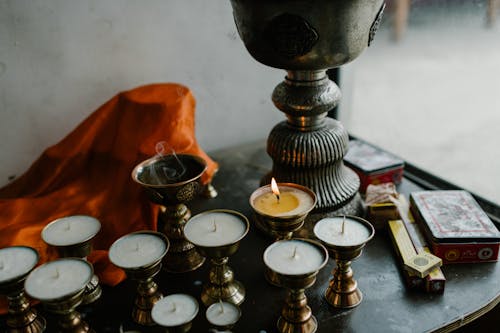 Free From above of small candles in copper butter lamps placed on table during traditional Tibetan ceremony in room Stock Photo