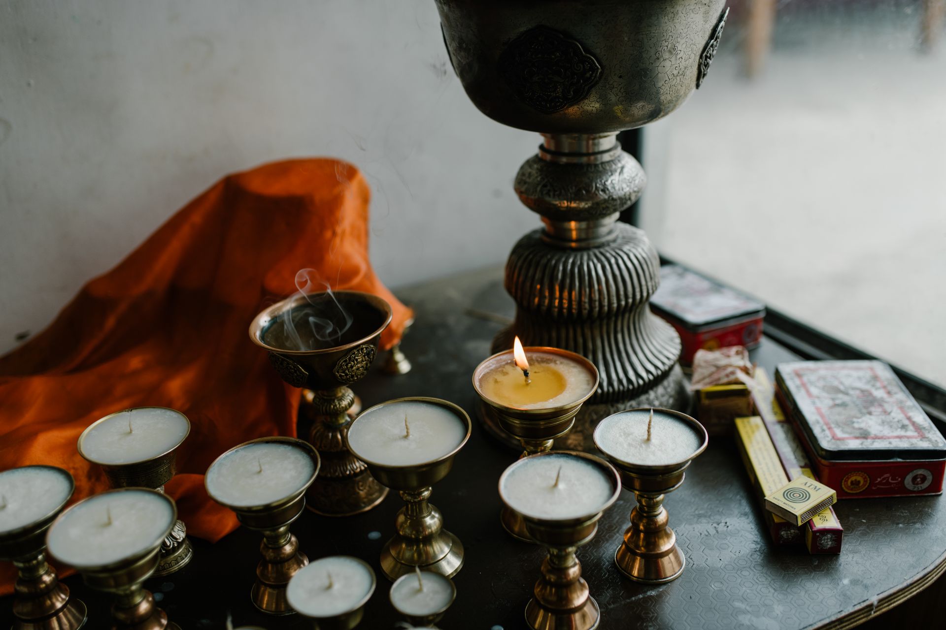 From above of small candles in copper butter lamps placed on table during traditional Tibetan ceremony in room