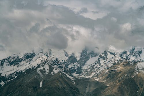Snowy mountain peaks hidden under cloudy sky