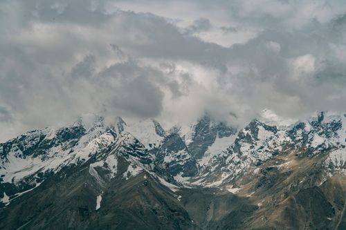 Free Spectacular scenery of gray clouds floating in sky over rocky mountains with sharp peaks covered with snow Stock Photo