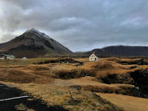 Free Picturesque view of a solitary house near a mountain in Arnarstapi, Iceland, under cloudy skies. Stock Photo