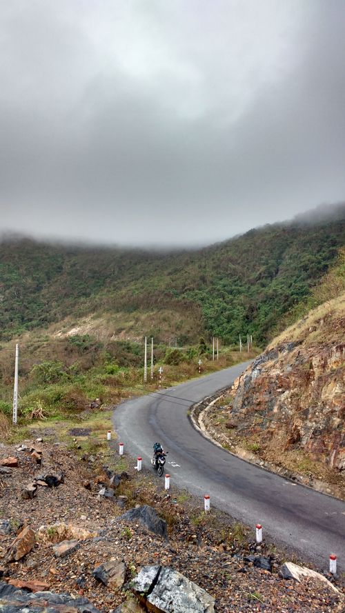 Free Motorcyclist rides along a winding road in the misty hills of rural Vietnam. Stock Photo