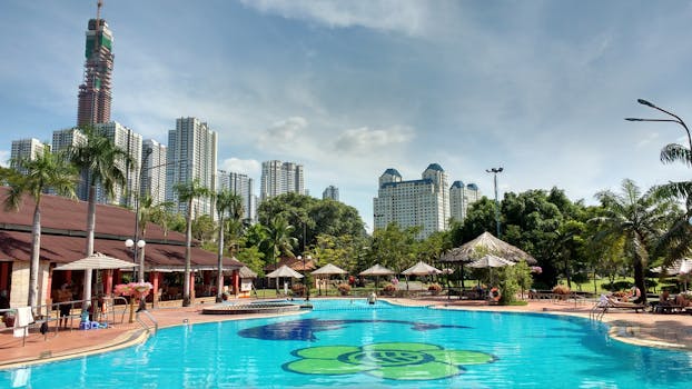 Serene resort pool with skyscrapers and palm trees in Ho Chi Minh City, a perfect summer getaway.