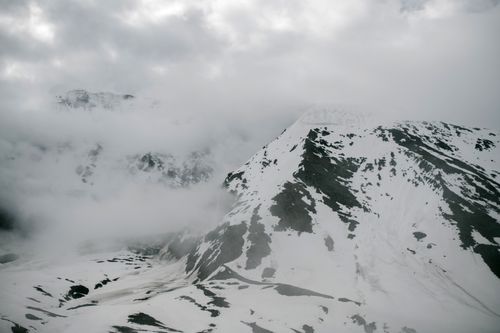 Free Breathtaking landscape of huge rocky mountain range covered with snow against cloudy sky in winter Stock Photo