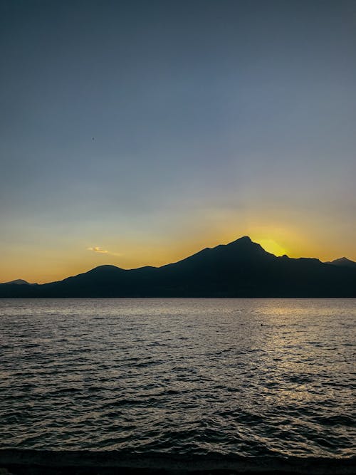 Silhouette of Mountain Near Body of Water during Sunset