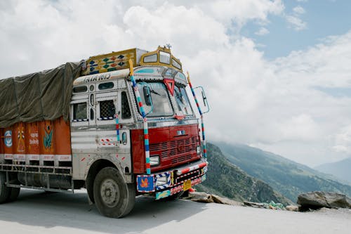 Aged truck driving in mountainous valley in sunlight