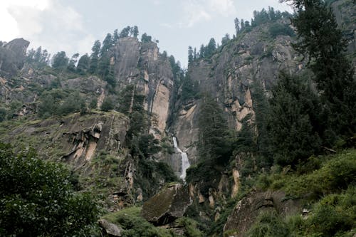 Picturesque rocky ravine with waterfall and green vegetation
