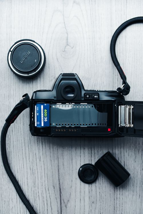 Free A classic vintage film camera, lens, and film roll on a wooden surface, evoking nostalgia and retro photography. Stock Photo