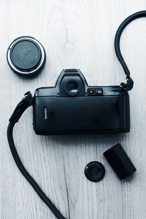 Free A retro film camera with lens and accessories on a wooden surface. Ideal for vintage photography themes. Stock Photo