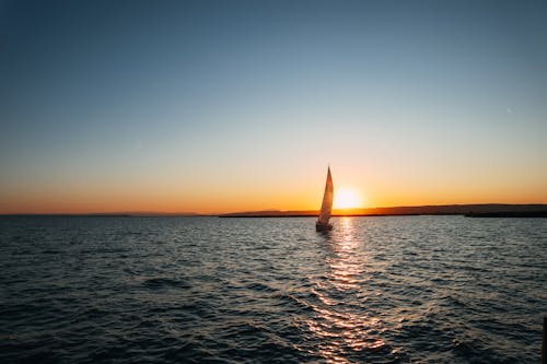 Picturesque seascape of endless sea with rippled water and boat sailing on water at sundown