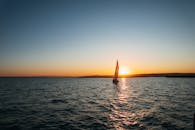 Lonely sailboat floating on rippling sea at sunset