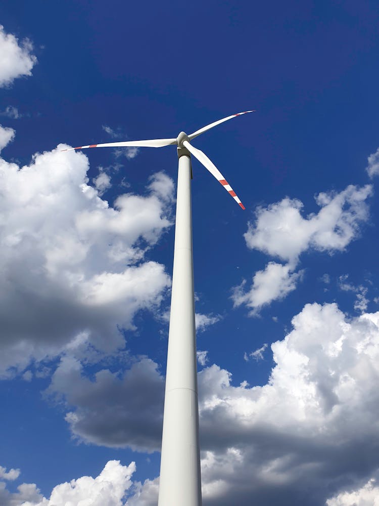 White Wind Turbine Under Blue And Cloudy Sky