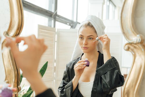 Free Woman in Black Robe Holding a Dropper and a Bottle Stock Photo
