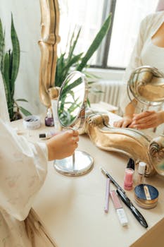 梳妆台前，一个女人双手持镜，周围摆满了化妆品